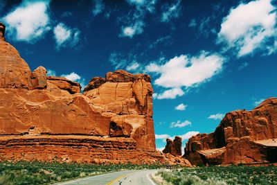 Low angle view of rock formations at arches national park against cloudy blue sky