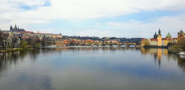 Bridge over river by buildings against sky in city