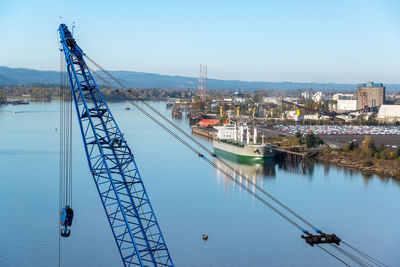 Cranes at harbor against sky