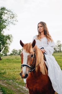 Young woman riding horse on field