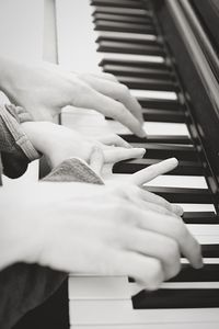 Cropped hands of mother and child playing piano