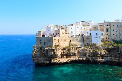 Buildings in sea against clear blue sky