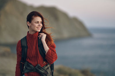 Young woman standing against sea