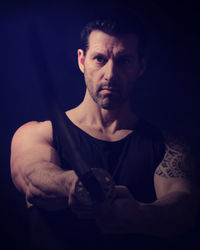 Close-up of young man with arms crossed against black background