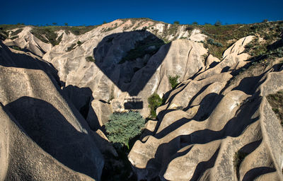 Shadow of hot air balloon on rock formations at cappadocia