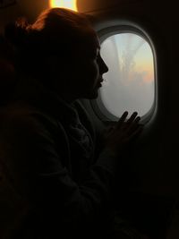 Rear view of woman looking through window in airplane 