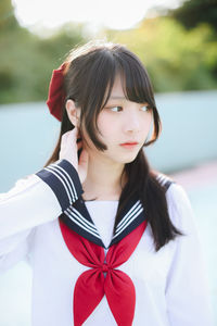 Portrait of young woman standing against wall