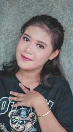 Portrait of young woman standing against wall