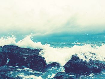 Waves splashing on sea against sky