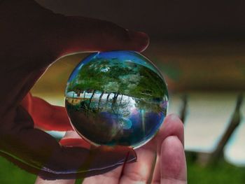 Close-up of hand giving crystal ball to person