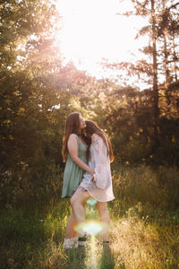 Lesbian couple romancing in forest during summer