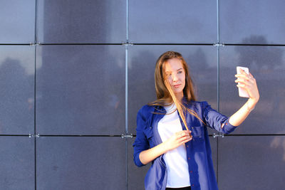 Portrait of woman standing against wall