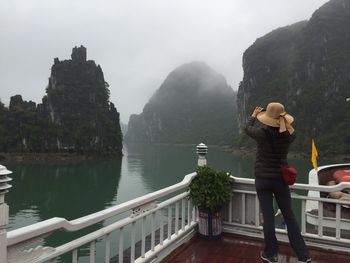 Rear view of woman standing against rock formations at halong bay