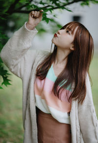 Portrait of young woman standing against plants