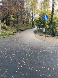 Road sign by trees during autumn