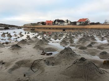 Houses on beach by buildings against sky