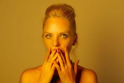 Close-up portrait of young woman against yellow background