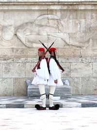 Woman with umbrella standing against wall