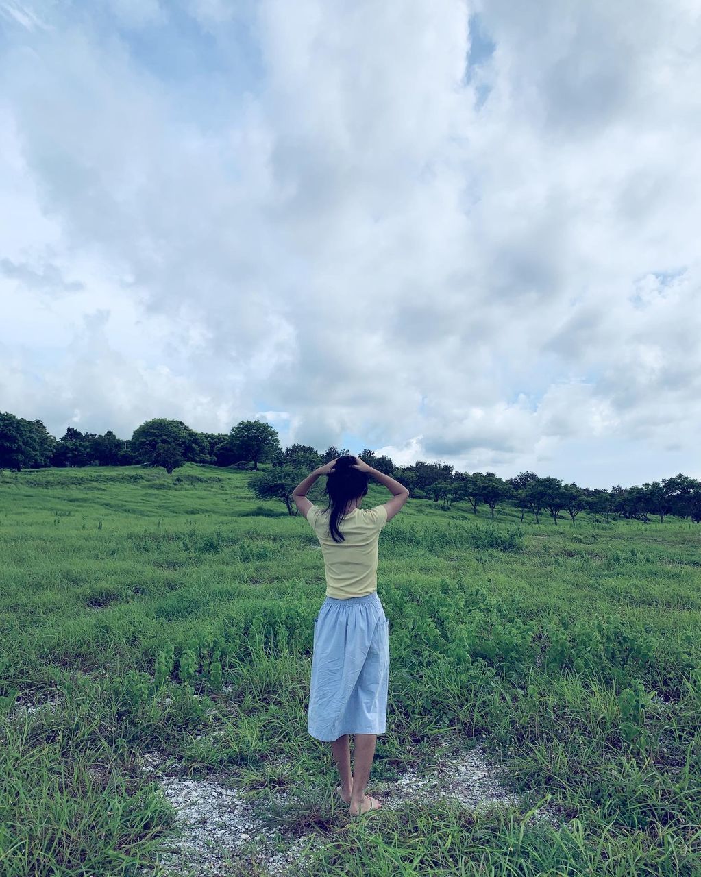 REAR VIEW OF A PERSON STANDING ON FIELD