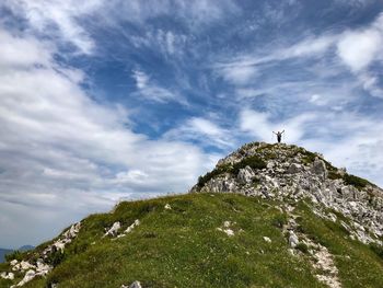 Low angle view of cross on rock against sky