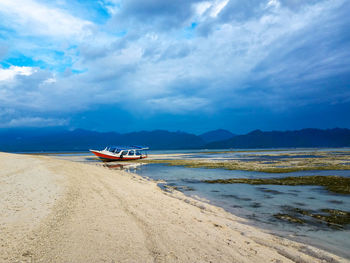 Boat moored on beach against sky