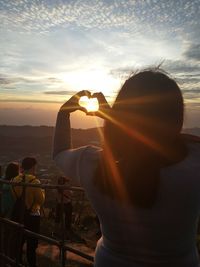 Rear view of woman photographing at sunset