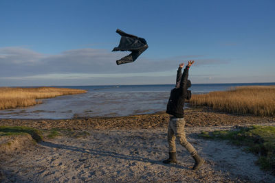 Man jumping on beach against sky