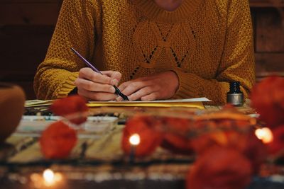 Midsection of woman writing with fountain pen