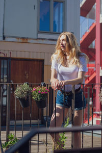 Woman with blond hair standing by railing in balcony