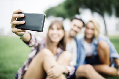 Young woman taking selfie with friends on field