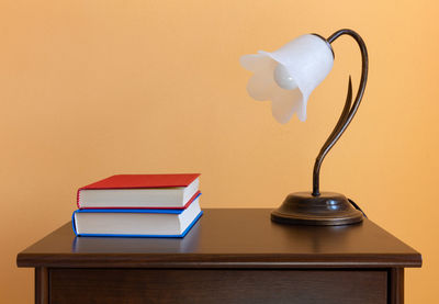 Close-up of electric lamp on table against wall at home