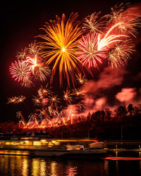 Low angle view of firework display over river against sky