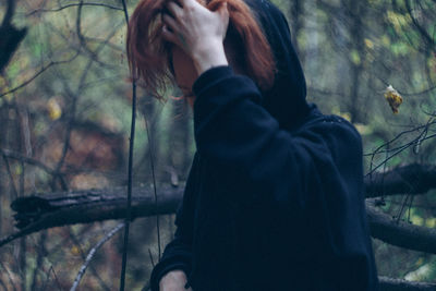 Midsection of woman standing by trees in forest