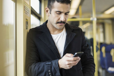 Young man using mobile phone in tram