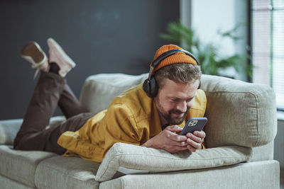 Young man using mobile phone while sitting on bed at home