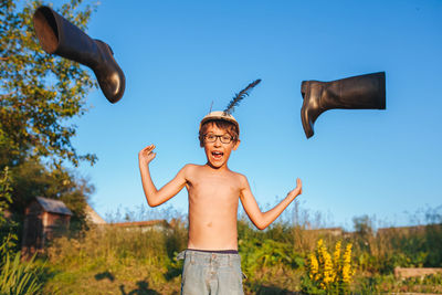 Full length of happy boy with arms raised against sky