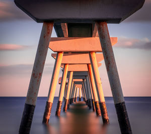 Pier amidst sea against sky during sunset