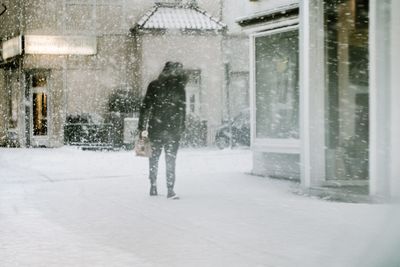 Rear view of people walking on road in city