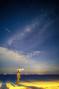 Rear view of man standing on mountain against sky at night