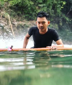 Portrait of young man on wooden raft in river