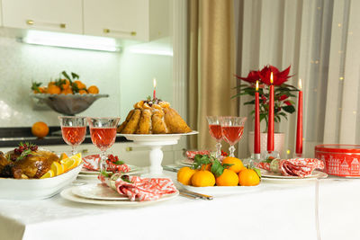 A festive table with baked chicken, tangerines, candles, cake and glasses of wine. holiday.