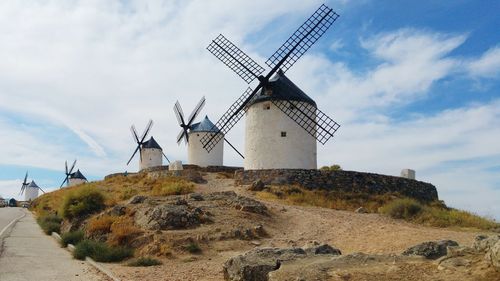 Traditional windmill on countryside landscape against cloudy sky