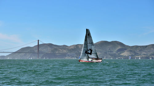 Boat sailing in sea against clear blue sky