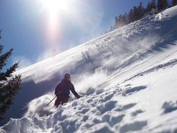 Man skiing in powder backlit by sun