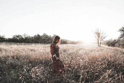 Woman standing on field against clear sky