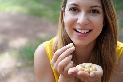 Close-up of healthy girl picking macadamia nuts outdoor. looks at camera.