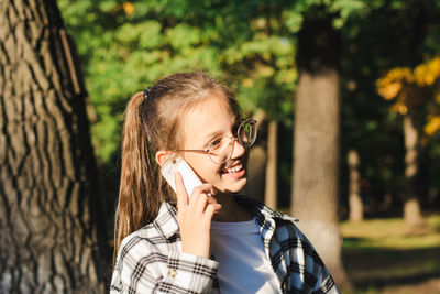 Cheerful girl in glasses talking on a dump phone outside