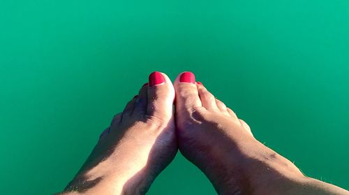 Relaxing on vacation, fleets with red nail polish in front of blue water, human leg  foot barefoot