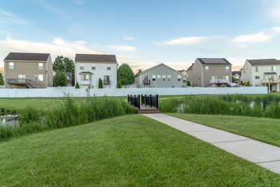 Lawn and houses on field against sky