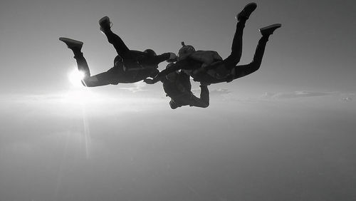 Low angle view of men jumping against sky